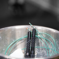 Corde à sauter noire avec câble enrobé vert dans bol de chalk